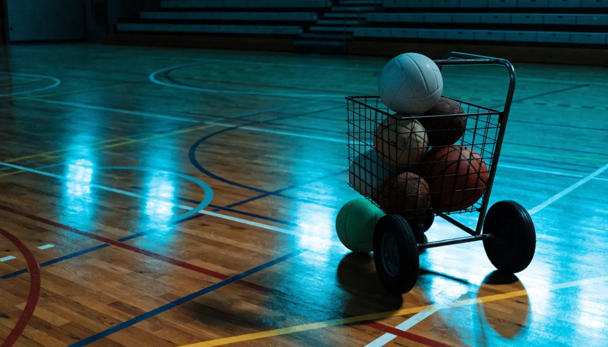 Ballwagen in einer Halle mit den Linien mehrerer Sportarten auf dem Boden, darin Volleyball, Basketball und Handball